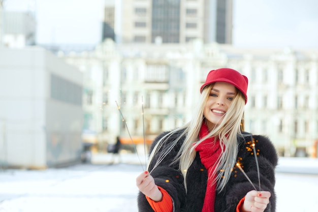 Niesamowity uśmiechający się model blondynka na sobie modną czapkę zabawy z ognie na ulicy. Miejsce na tekst