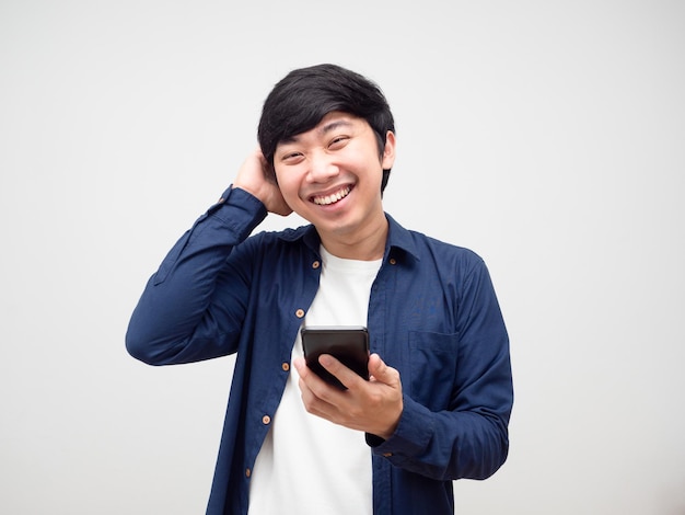 Nieśmiały mężczyzna dotyka głowy i trzyma uśmiechniętą twarz telefonu komórkowego na białym tle