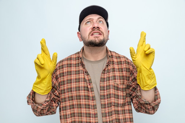 Niespokojny słowiański sprzątacz z gumowymi rękawiczkami krzyżującymi palce i patrzący w górę