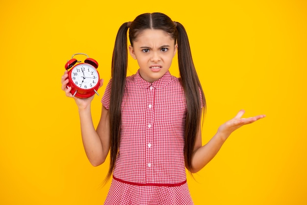 Nieszczęśliwa smutna dziewczyna nastolatka Dziecko trzymające zegar na żółtym tle Harmonogram dnia wcześnie rano Dziecko sprawdzające czas, nie spóźnij się Punktualne dziecko z alarmem Termin