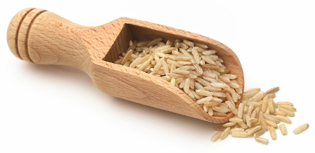 Nieugotowany brązowy ryż w drewnianej łyżce na białym
