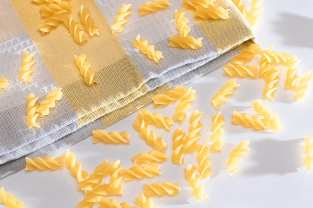 Zdjęcie nieugotowany makaron fusilli rozrzucony na białym stole