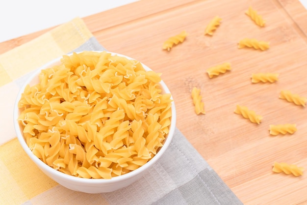 Nieugotowany Makaron Fusilli w Białej Misce na Drewnianej Tablicy