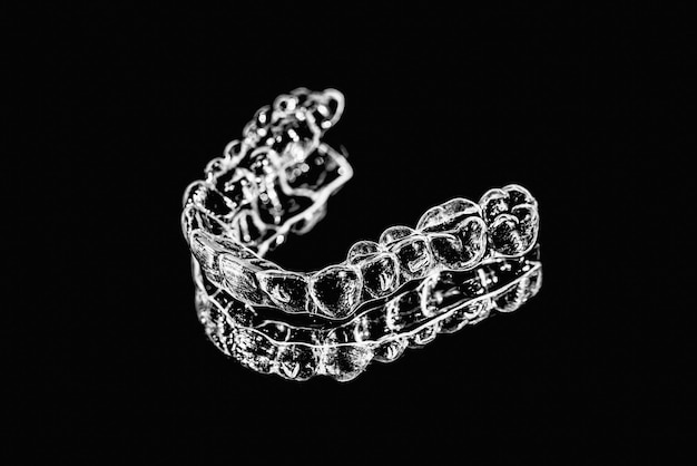 Niewidzialne urządzenia do utrzymywania zębów leżą na lustrze w gabinecie ortodontycznym
