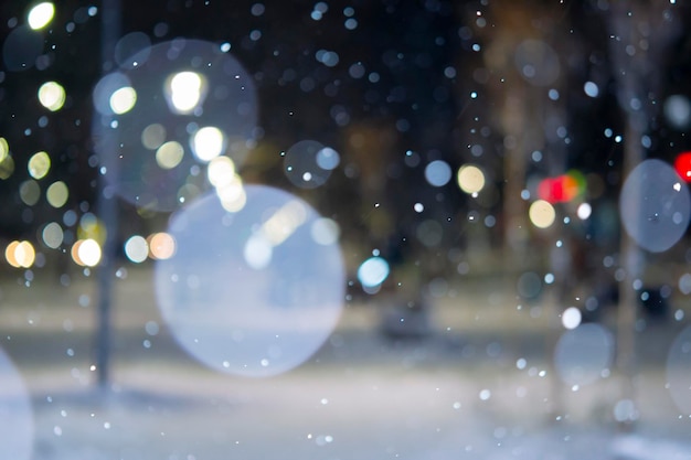 Niewyraźne tło widok na miasto światła padający śnieg noc ulica bokeh plamy