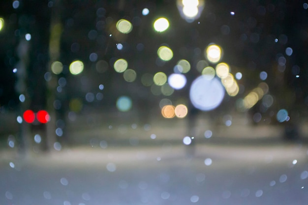 Niewyraźne tło widok na miasto światła padający śnieg noc ulica bokeh plamy