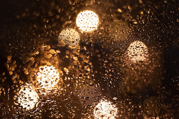 Niewyraźne tło z kroplami deszczu i światłami.