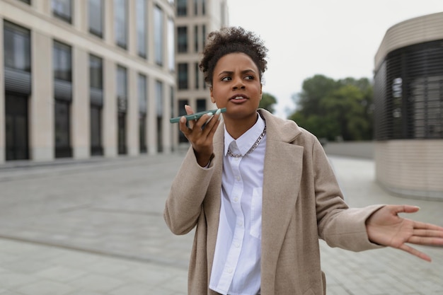 Niezadowolona afroamerykanka rozmawia przez telefon komórkowy bez użycia rąk, machając rękami przed