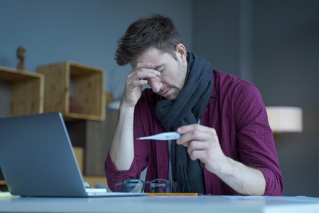 Niezadowolony Austriacki Mężczyzna Freelancer Sprawdzający Temperaturę Ciała W Pracy Trzymający Termometr