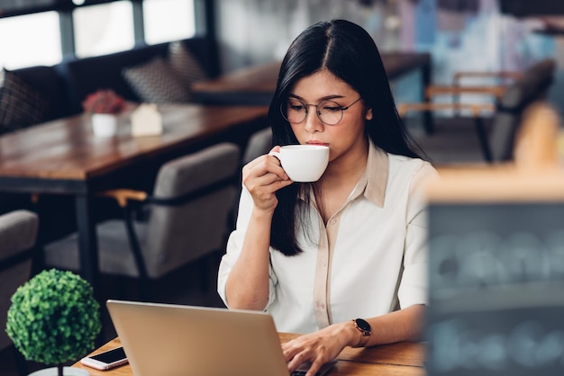 Niezależna kobieta pracująca w stylu życia z laptopem, pije kawę w kawiarni z kawą