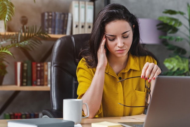 Niezależna kobieta pracująca z laptopem ma ból głowy i stres w pracy