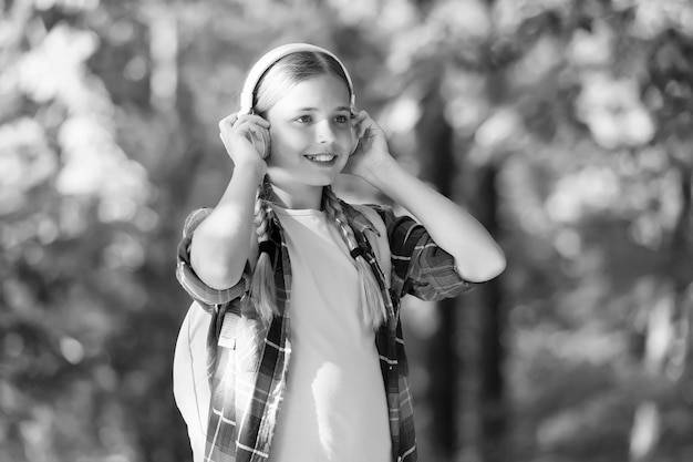 Niezbędna część współczesnego życia Mała dziewczynka nosi słuchawki naturalne na zewnątrz Małe dziecko słucha muzyki Dźwięk HiFi Dźwięk cyfrowy Nowoczesna technologia Letnie wakacje i podróże Nowoczesny styl życia