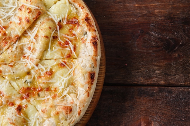 Niezdrowe jedzenie, złe nawyki, niezdrowe odżywianie, kalorie. Świeża pizza z gorącym serem podawana na rustykalnym drewnianym stole, płasko leżąca z wolnym miejscem na tekst.
