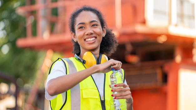 Niezgodna Afroamerykanka brygadzista pijąca butelkę wody po skończonej pracy