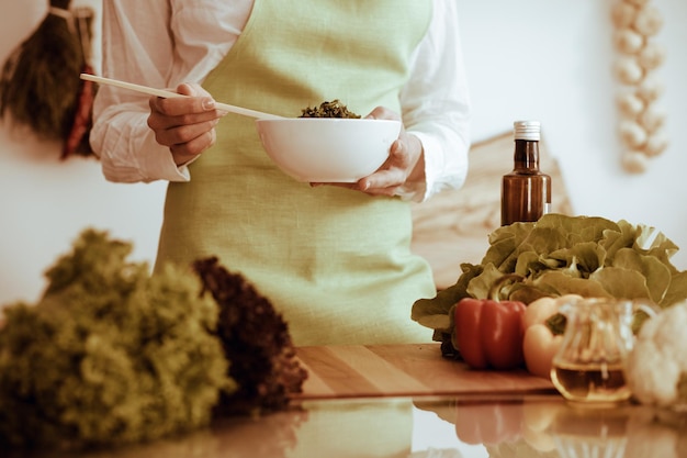 Nieznane ludzkie ręce, gotowanie w kuchni. Kobieta jest zajęta sałatką jarzynową. Zdrowy posiłek i wegetariańska koncepcja żywności.