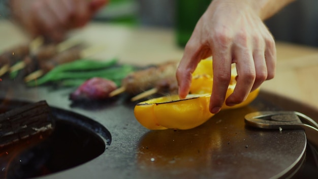 Zdjęcie nieznany facet gotuje jedzenie na grillu na zewnątrz żółta papryka na siatce