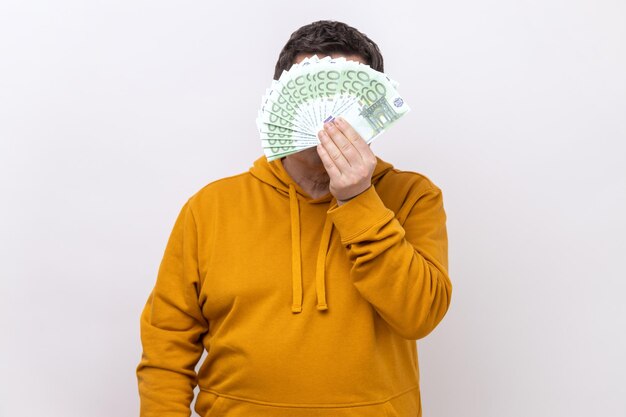 Nieznany mężczyzna ukrywający twarz za fanem setek euro rachunków za duże wygrane zakłady
