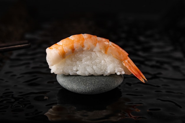 Nigiri sushi z krewetkami na kamieniu i czarnym błyszczącym talerzu