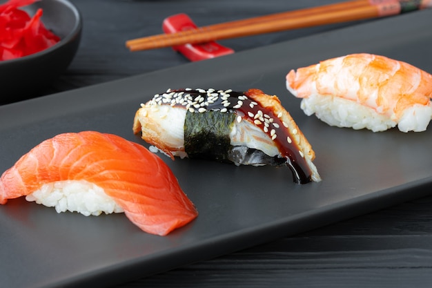 Nigiri sushi z łososiem i krewetką podane na czarnym talerzu ceramicznym