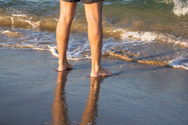 Zdjęcie niska część człowieka stojącego na brzegu plaży