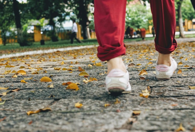 Zdjęcie niska część kobiety idącej po chodniku w parku