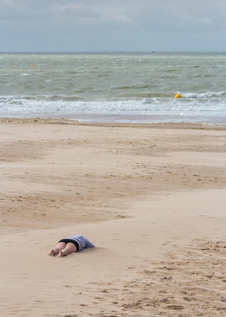 Zdjęcie niska część kobiety leżącej na piasku na plaży