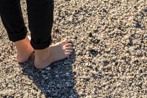 Zdjęcie niska część kobiety stojącej na kamieniach na plaży