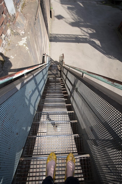 Zdjęcie niska część kobiety stojącej na metalowej schodach w budynku przemysłowym