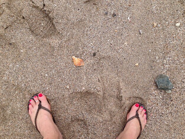 Niska część kobiety stojącej na piaszczystej plaży