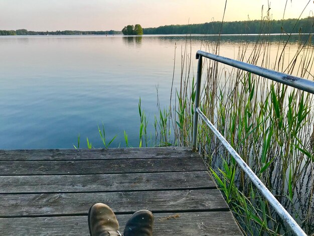 Zdjęcie niska część osoby na molo nad jeziorem