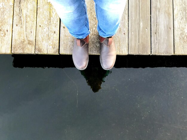 Zdjęcie niska część osoby stojącej na molo nad jeziorem
