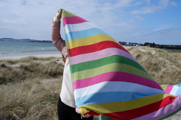 Zdjęcie niska część osoby trzymającej ręcznik na plaży przeciwko niebu