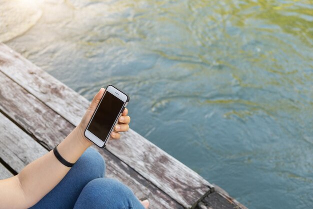 Zdjęcie niska część osoby trzymającej telefon komórkowy nad rzeką