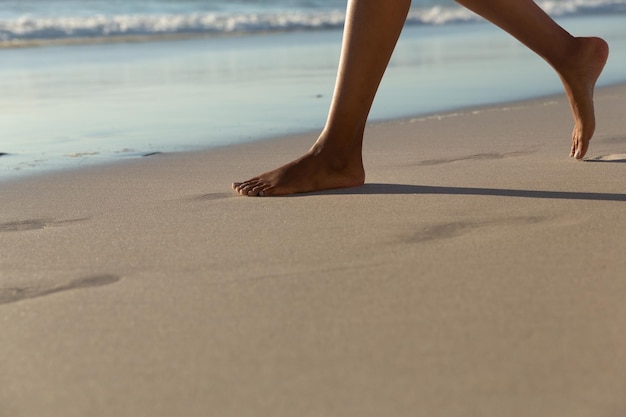 Niska sekcja kobiety rasy mieszanej na plaży ćwiczącej jogę podczas zachodu słońca. zdrowy wypoczynek na świeżym powietrzu nad morzem.