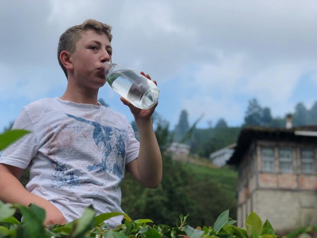 Zdjęcie niski anioł widzi człowieka pijącego wodę, stojącego na tle nieba