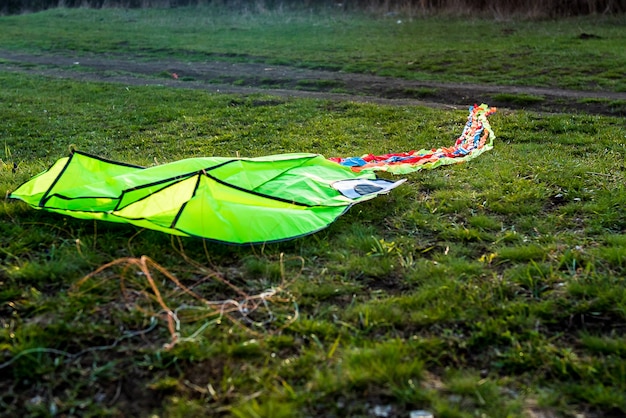 Niski kąt ujęcia papierowego latawca wpadającego na trawę oświetloną przez słońce od tyłu