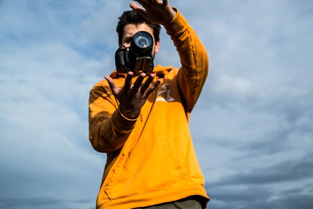 Niski kąt widoku człowieka fotografującego kamerą na tle nieba