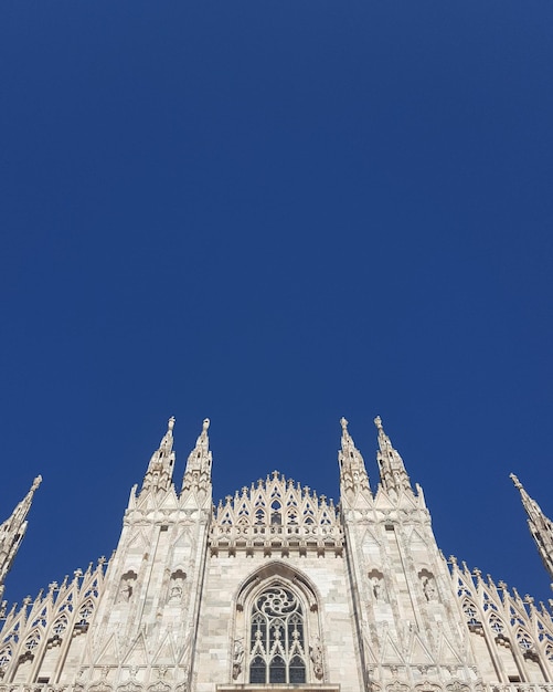 Niski kąt widoku Duomo di Milano na tle jasnego niebieskiego nieba