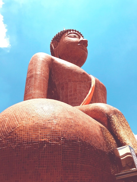 Zdjęcie niski kąt widoku dużej posągu buddy na tle niebieskiego nieba w słoneczny dzień