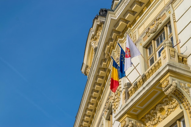 Zdjęcie niski kąt widoku flag na budynku na tle jasnego niebieskiego nieba