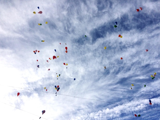 Zdjęcie niski kąt widoku kolorowych balonów z heliu latających na chmurowym niebie
