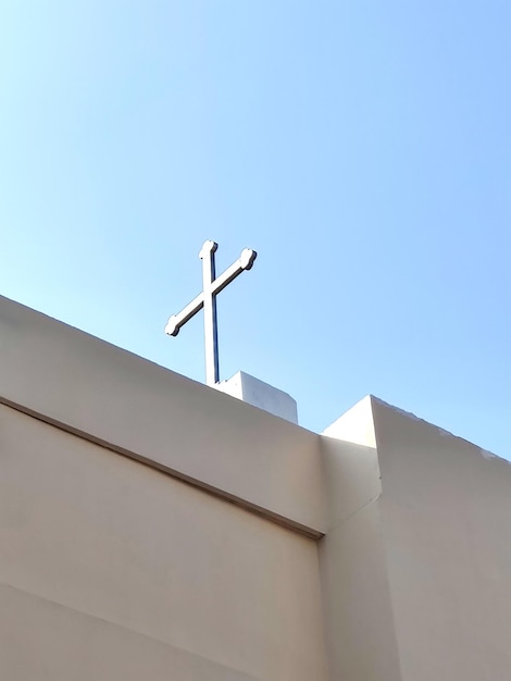 Niski kąt widoku krzyża chrześcijańskiego na jasnym niebie