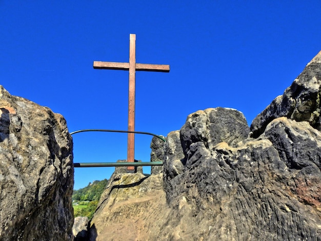 Zdjęcie niski kąt widoku krzyża obok ściany na jasnym niebie