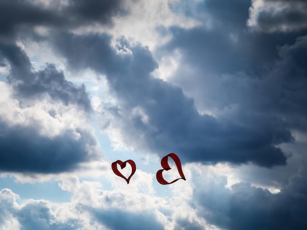 Zdjęcie niski kąt widoku latających na chmurowym niebie latających latawców w kształcie serca