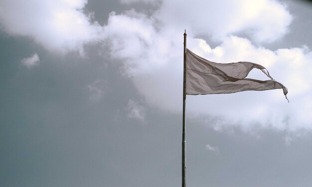 Zdjęcie niski kąt widoku machającej flagi na słupie na tle nieba