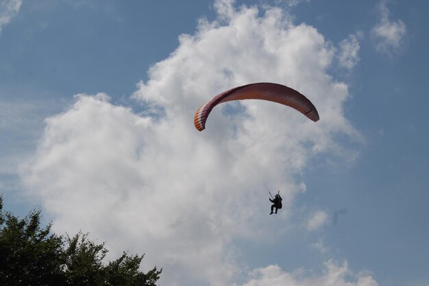 Zdjęcie niski kąt widoku osoby latającej na paragliderze na tle nieba