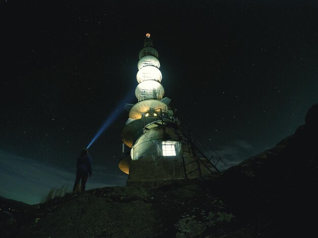 Zdjęcie niski kąt widoku osoby patrzącej na budowlę w nocy