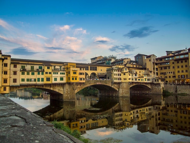 Niski kąt widoku ponte vecchio na rzece Arno na tle nieba