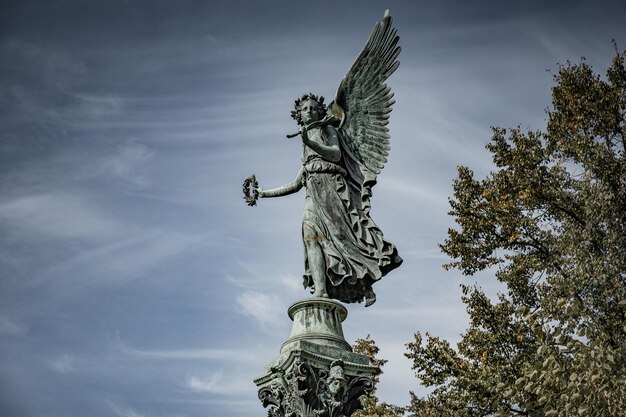 Zdjęcie niski kąt widoku posągu anioła na chmurnym niebie