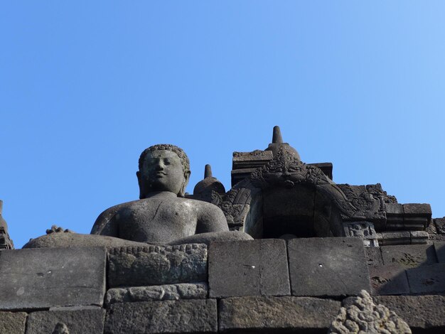 Niski kąt widoku posągu na tle jasnego niebieskiego nieba w Borobudur